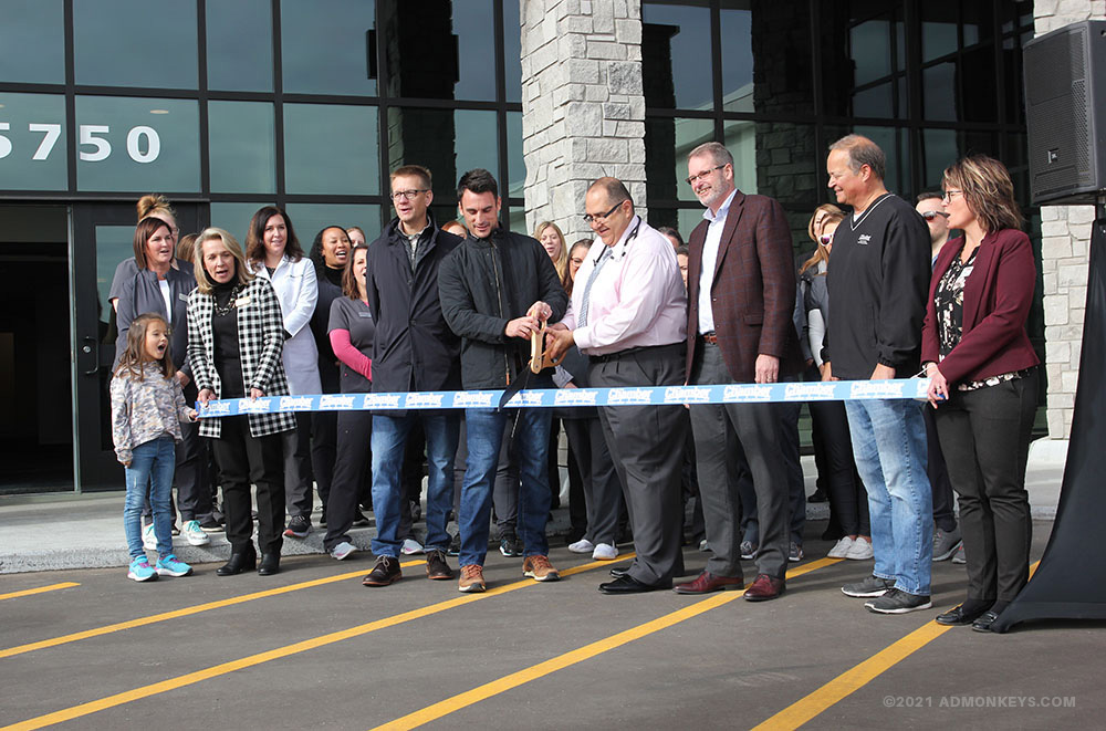 A group of people are cutting a ribbon in front of a new building.