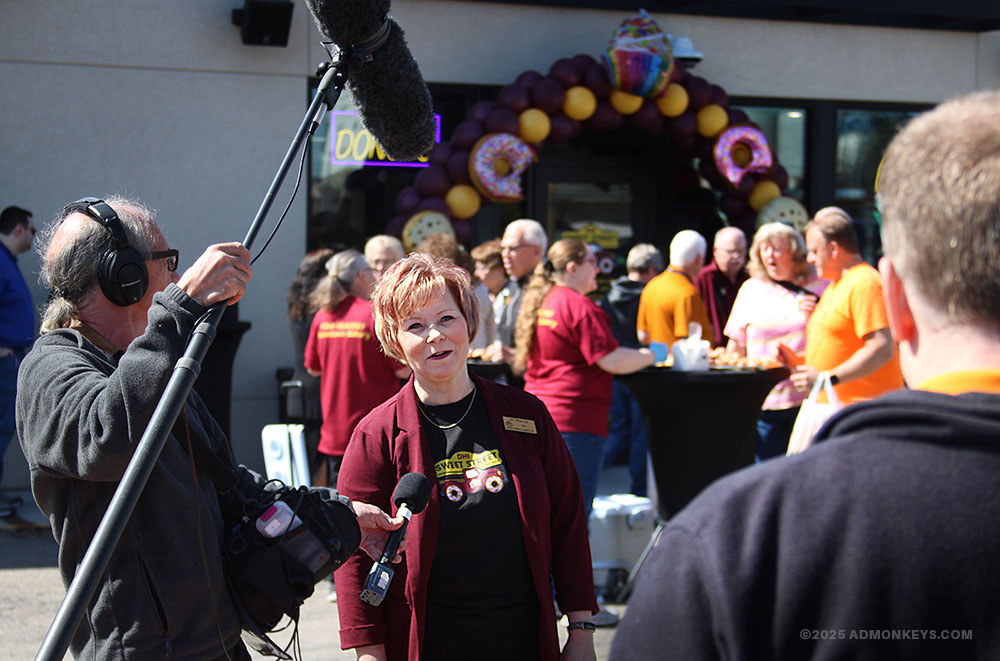 A camera crew interviews a lady for a grand opening event.