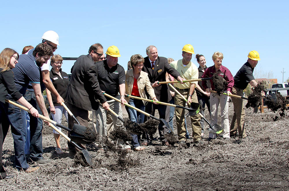 A row of people with hard hats start the groundbreaking ceremony.