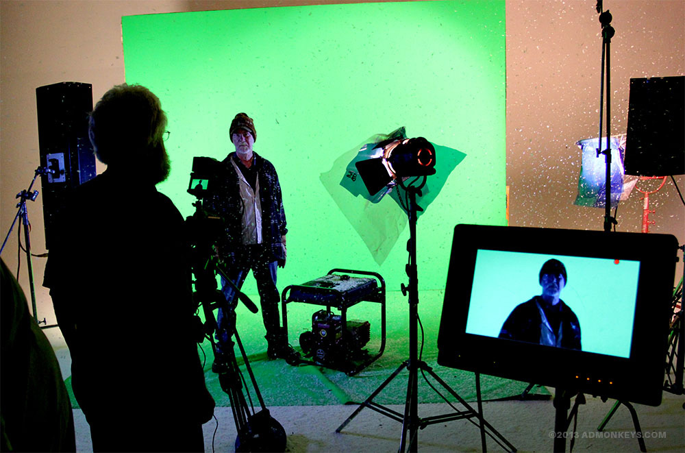 admonkeys_videoshoot_greenscreen_commercial+Tag A man stands in front of a green screen for a video shoot with fake snow flying around the studio.